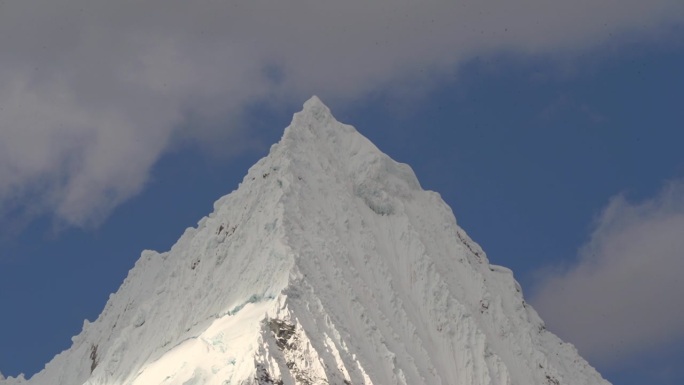 在秘鲁华斯卡兰的白科迪勒拉安第斯山脉的高山上，拉古纳帕隆泻湖的一座金字塔形山的冰川被冰雪覆盖，阳光明