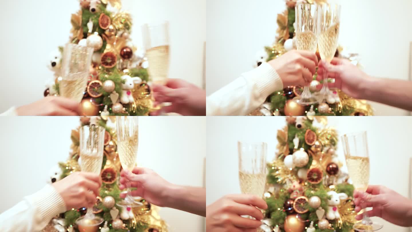节日慢动作视频，手拿着香槟酒杯，叮当作响，溅到四周，背景是装饰过的圣诞树