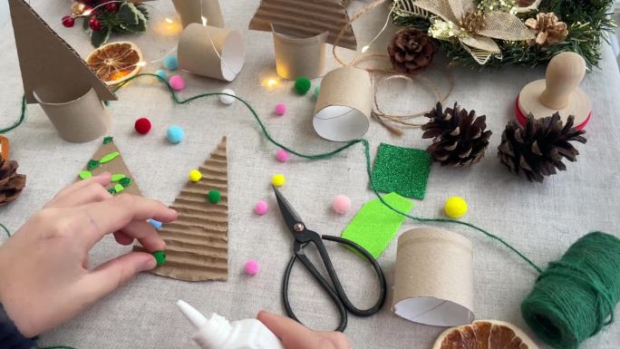 手工圣诞树装饰。孩子们的手用彩色球装饰纸板做成的圣诞树的特写。零废物概念。