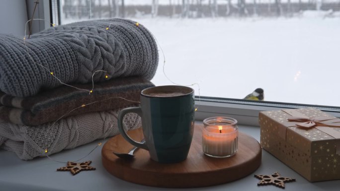冬天窗台上的静物。窗台上的蓝色陶瓷杯热咖啡。圣诞装饰的背景。温馨的家庭照片。采购产品温暖的羊毛针织毛