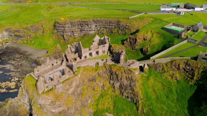 在北爱尔兰的邓卢斯城堡上空逆时针旋转的航拍轨道