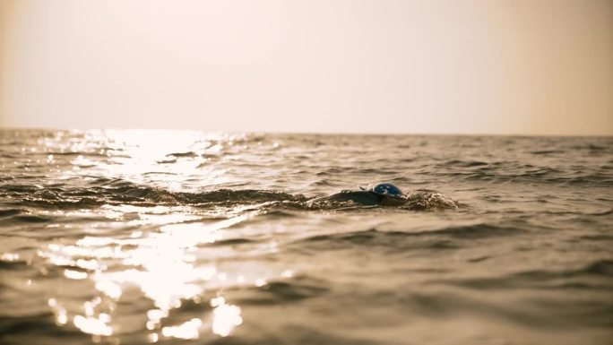 日落时女子在海中游泳的锁定镜头