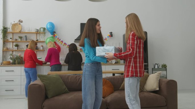 快乐的可爱的十几岁的生日女孩在聚会室内带着礼物会见朋友