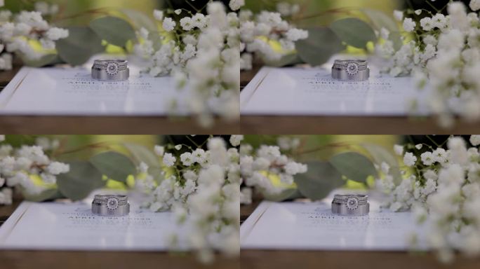 婚礼请柬上环绕着婴儿呼吸鲜花的结婚戒指。