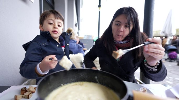瑞士奶酪食品——母亲和孩子在十二月享用传统的欧洲美食，人们吃奶酪和面包