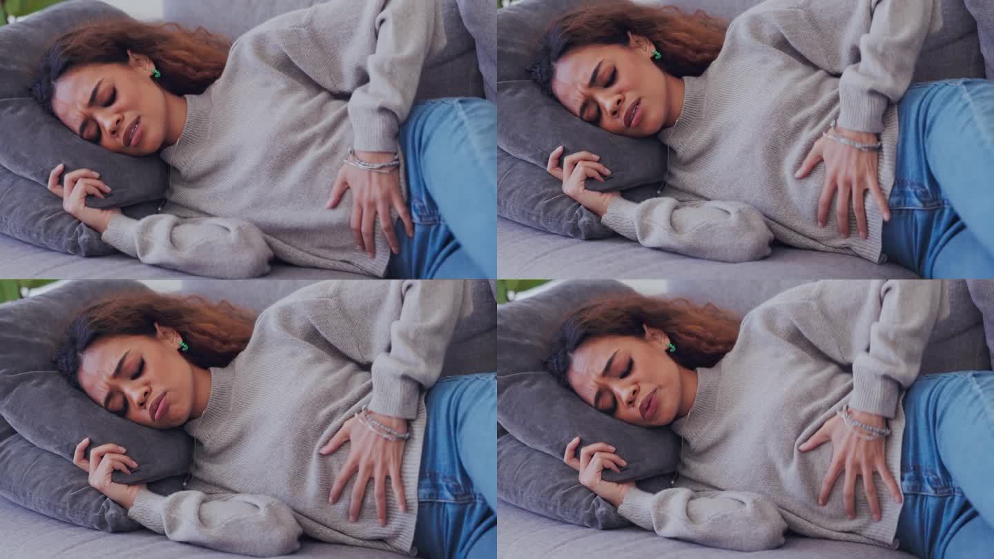 患有子宫内膜异位症、结肠危象和肠绞痛便秘的人、生病和经期疼痛在家沙发上。混血女性，胃部病毒引起的胃痛