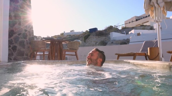 慢镜头:一名男子在他的度假屋户外的私人热水浴缸里放松