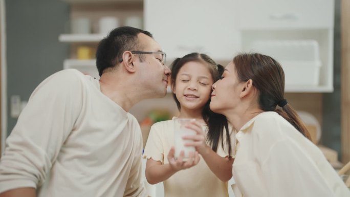 亚洲父母分享衷心的时刻，亲吻他们笑着的女儿:捕捉到真正的家庭之爱。