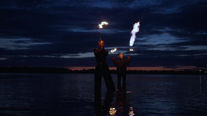 专业特技女演员和特技男演员用火表演，令人惊叹的河岸边的火表演