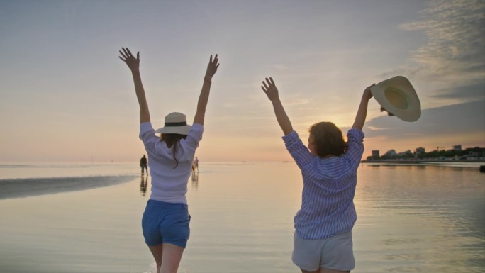 两位女性朋友在日落时分走在沙滩上