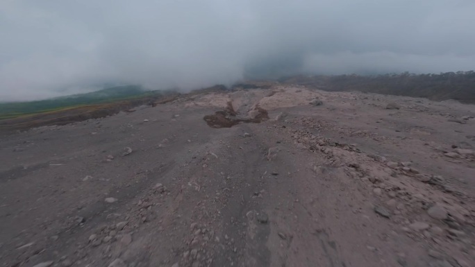 FPV无人机在带有岩石表面的活火山斜坡上快速俯冲飞行