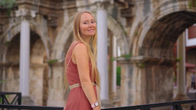 在这段迷人的影片中，一名年轻女子在安塔利亚参观著名的旅游景点——哈德良门。她站在雄伟的拱门前，上面装