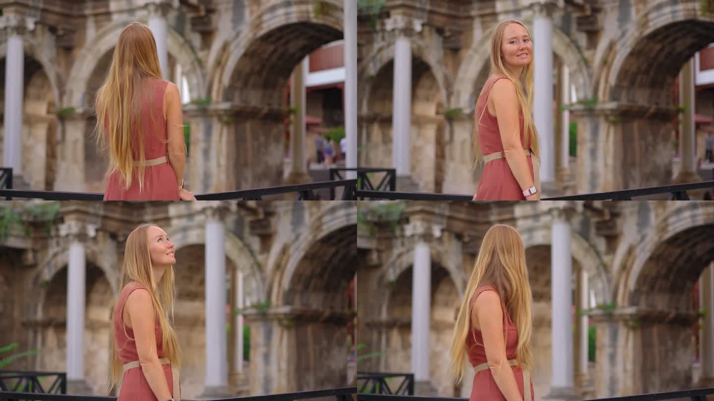 在这段迷人的影片中，一名年轻女子在安塔利亚参观著名的旅游景点——哈德良门。她站在雄伟的拱门前，上面装