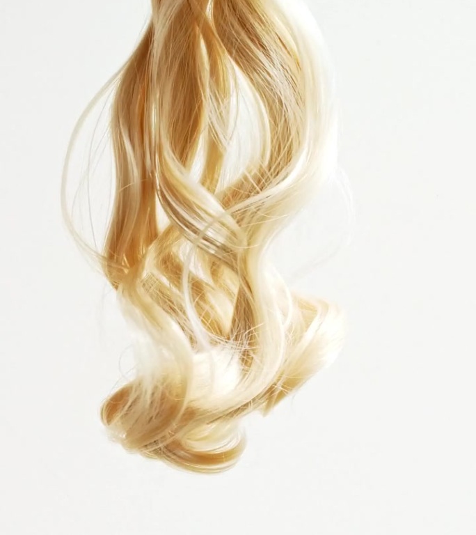一束束金色的、有光泽的、波浪状的头发。缓慢的运动。护发美容美发。天然化妆品。发色盘