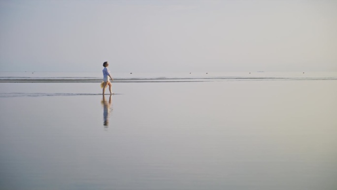 日落时分，一名女子走在沙滩上的浅水里