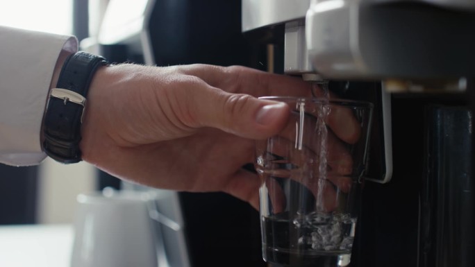 用手从饮水机中将淡水倒入玻璃杯