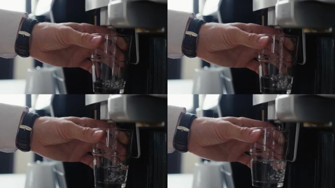 用手从饮水机中将淡水倒入玻璃杯