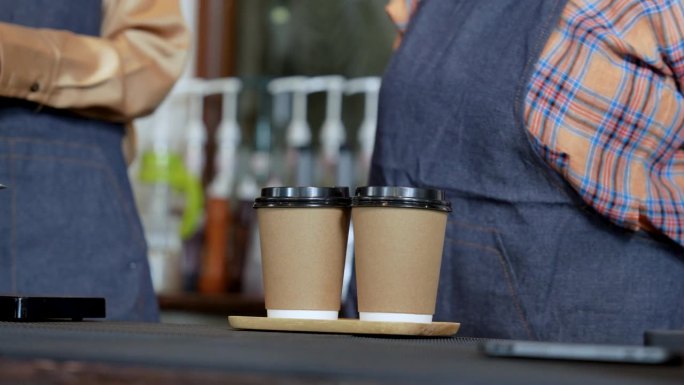 亚洲老年;年轻的咖啡师在咖啡机上工作，店主在帮顾客倒咖啡。咖啡厅餐饮服务小企业主餐饮行业的概念。