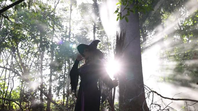 一个女巫拿着一把魔法扫帚走进森林，年轻的女巫骑着扫帚飞过森林