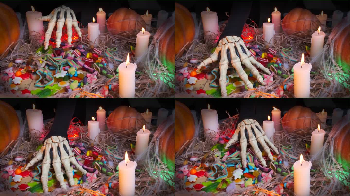 近距离观察，令人毛骨悚然的骷髅手偷偷摸摸地穿过糖果，抚摸着秋天节日蜡烛的色彩缤纷的糖果