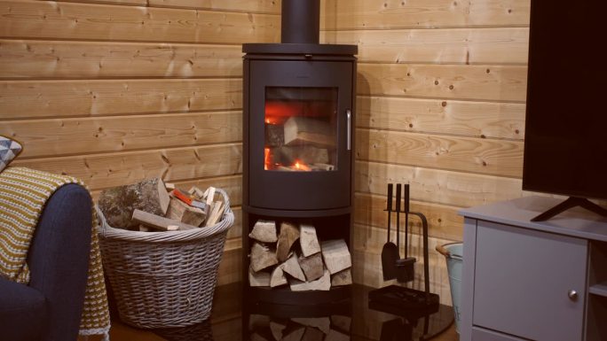 广角镜头，在一个小木屋里，用引火和圆木烧柴的火炉里刚刚开始起火。