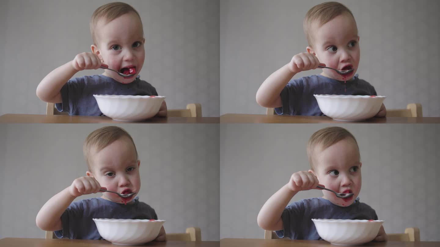 小婴儿蹒跚学步的孩子用手里的勺子喝汤，学习自己喂食