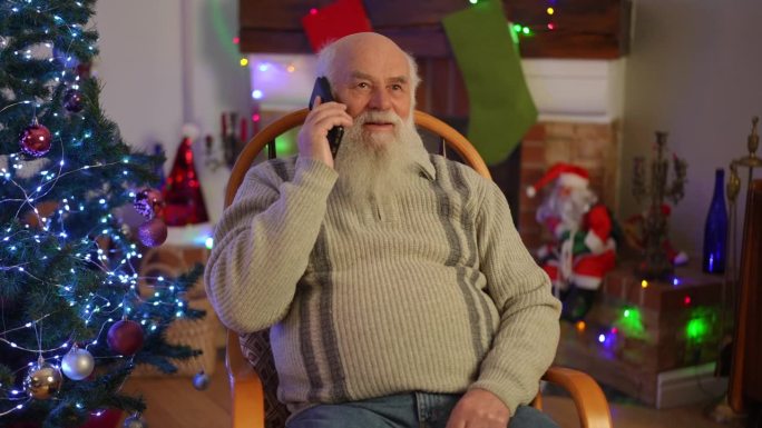 圣诞节，坐在圣诞树旁的扶手椅上，孤独的老祖父在打电话。