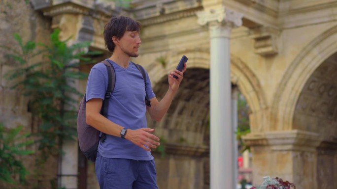在这段引人入胜的影片中，一位年轻的游客在安塔利亚参观著名的旅游景点——哈德良门。他站在雄伟的拱门前，