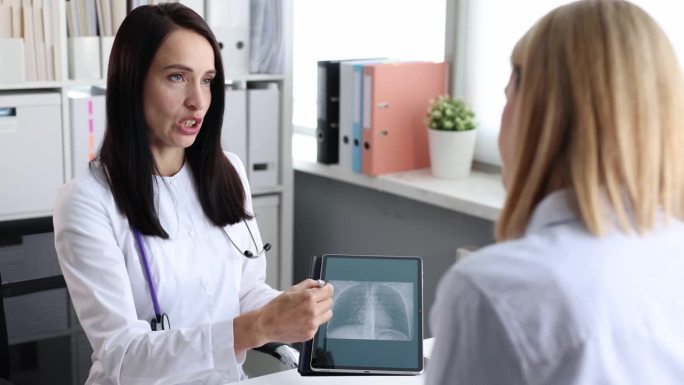 医生向病人展示数码平板电脑和肺部的CT扫描