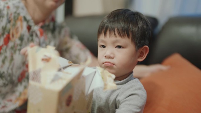 节日的喜悦:小男孩的快乐与家人一起打开圣诞礼物。