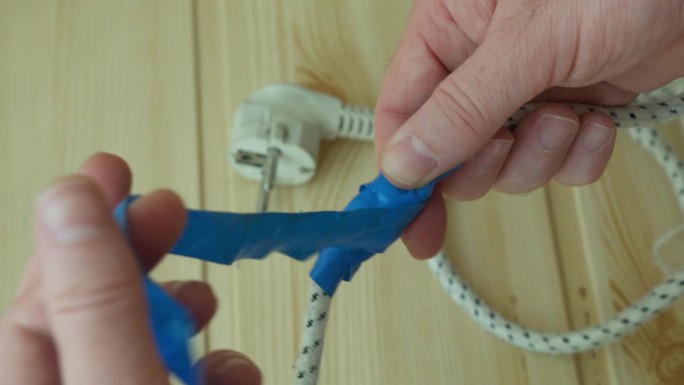 用蓝色绝缘胶带自己动手修理损坏的电线。
