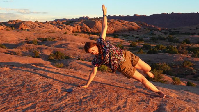 一名女游客在犹他州沙漠中的一块岩石上摆姿势