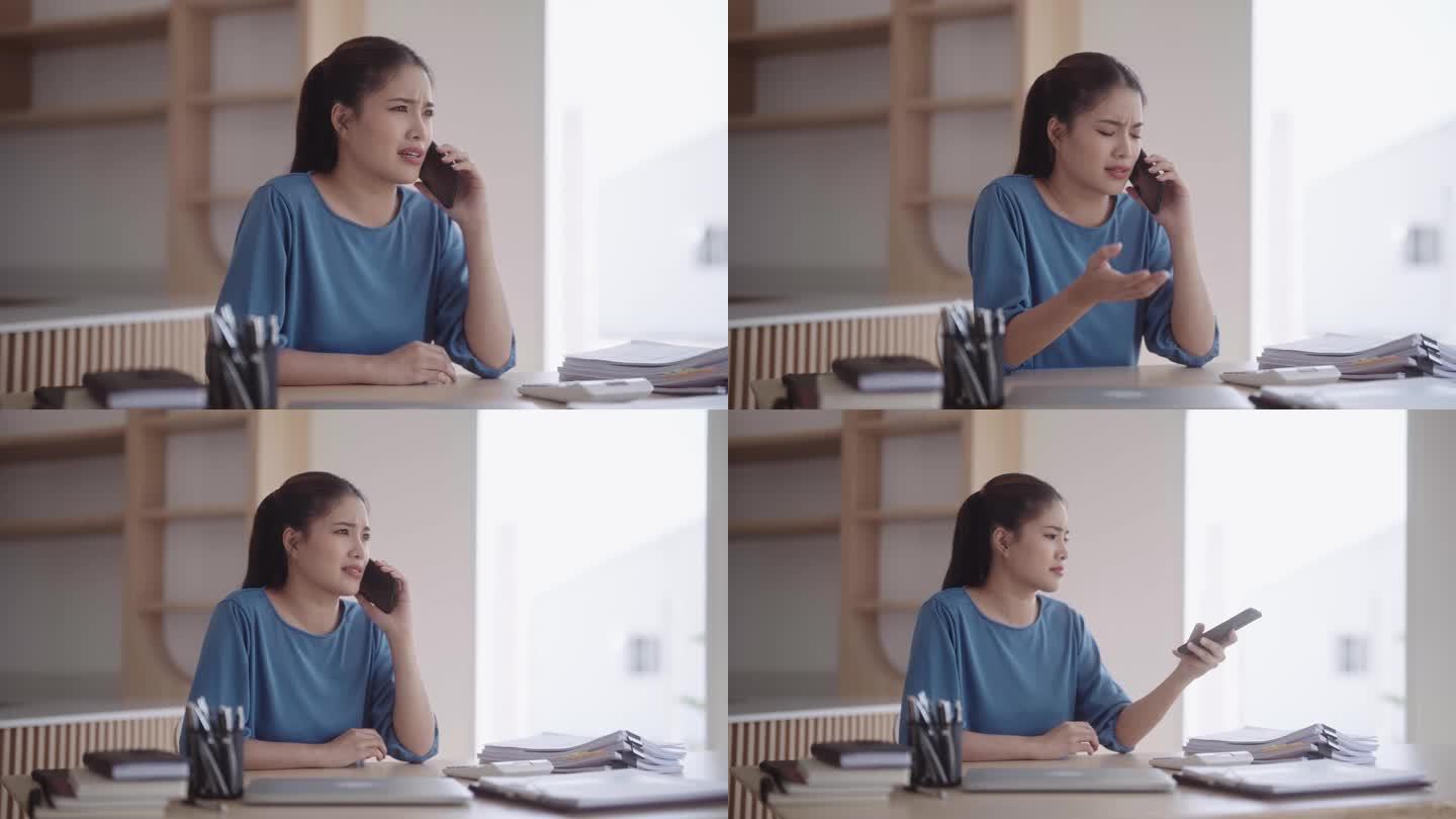 一个沮丧沮丧的亚洲女人，穿着休闲服，正在进行一场激烈而难以理解的电话交谈。她心情沉重地把电话放在餐桌