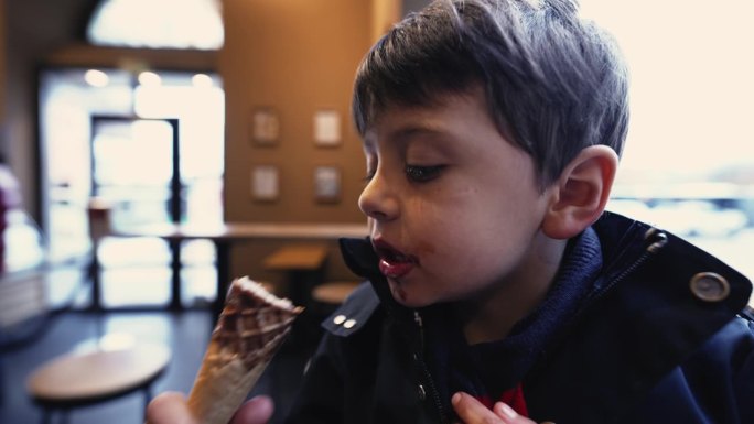 男孩在咖啡馆享用冰淇淋甜筒，背景是城市动态视图