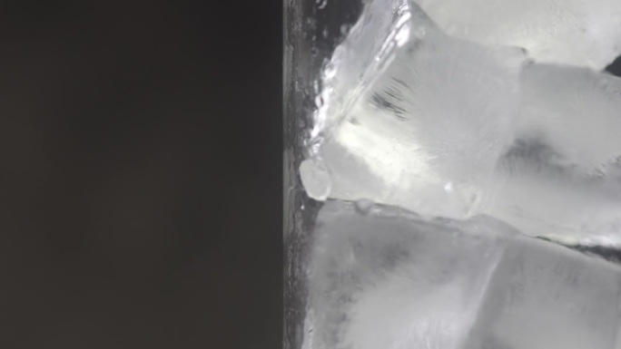 冰块放在透明玻璃中，在黑光背景下旋转拍摄。