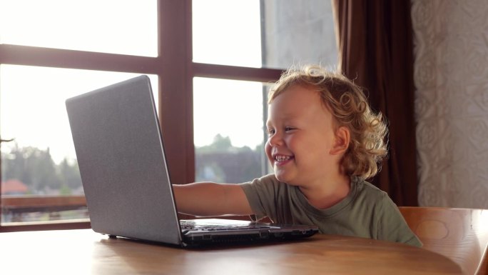 年轻开朗的孩子在笔记本电脑、触摸屏上从事在线学习