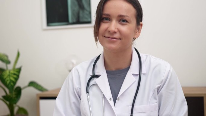 一名女医生微笑着对着镜头，在网上预约时热情地问候病人