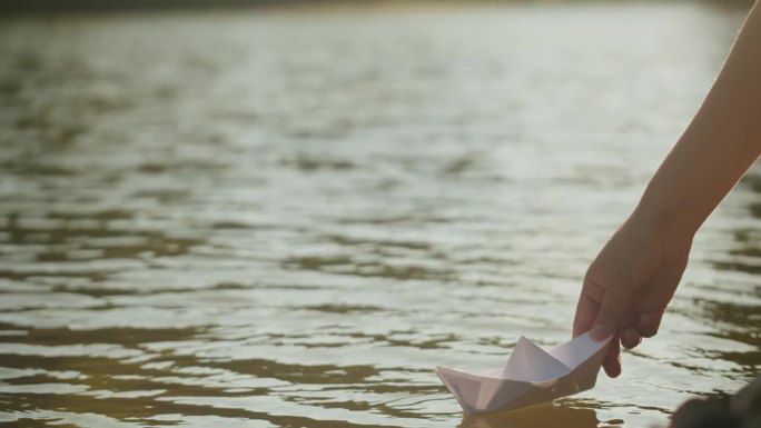 在公园里，人们把纸船放在水上。池塘上的折纸鹤。晴天的自然湖景