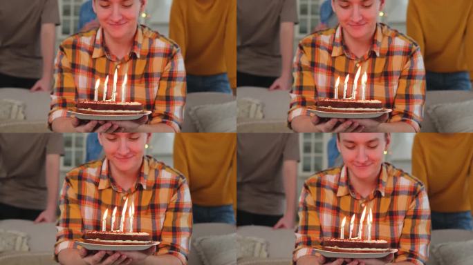 许个愿。戴着派对帽的男子吹灭了生日蛋糕上燃烧的蜡烛。生日派对快乐。一群朋友祝他生日快乐。人们在家里开