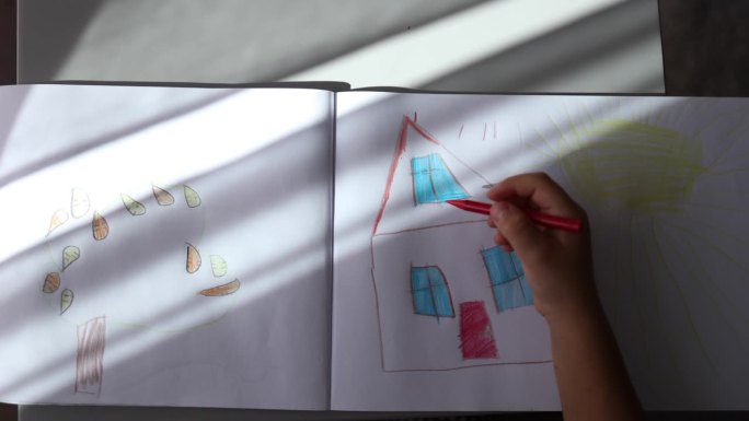 小女孩在相册里画画的俯视图。假期家居活动