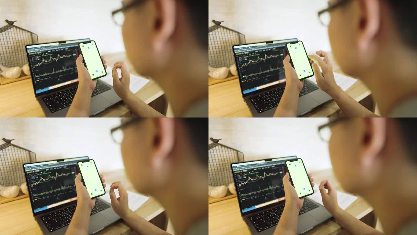 男子使用手机在垂直模式与绿色屏幕与笔记本电脑的背景