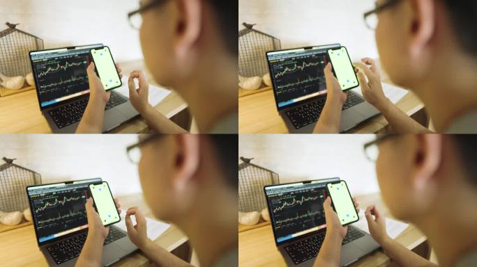 男子使用手机在垂直模式与绿色屏幕与笔记本电脑的背景