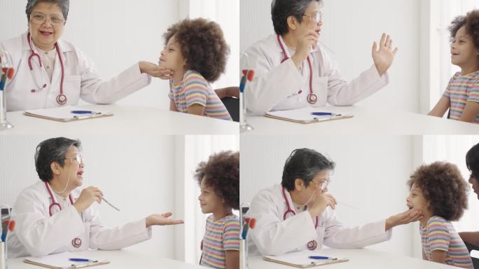 资深亚洲女医生治疗黑人儿童病人。女儿科医生正在使用压舌板检查幼儿的喉咙。