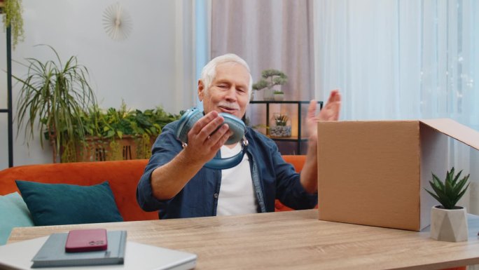 快乐的老人购物者打开耳机纸板箱送货包裹网购购买