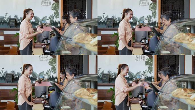 漂亮的亚洲女性顾客在面包店和咖啡店买蛋糕。围裙上的老店主卖主正在安排付款，而年轻的女士正在摆弄咖啡机