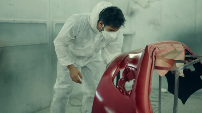 汽车细节的掌握:拉丁男性技术员提高车辆与喷漆。