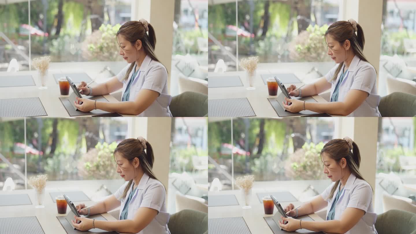 亚洲聪明的女医生穿着制服，用平板电脑和数字笔在咖啡馆工作或在家工作远程会议。医疗健康人的理念。