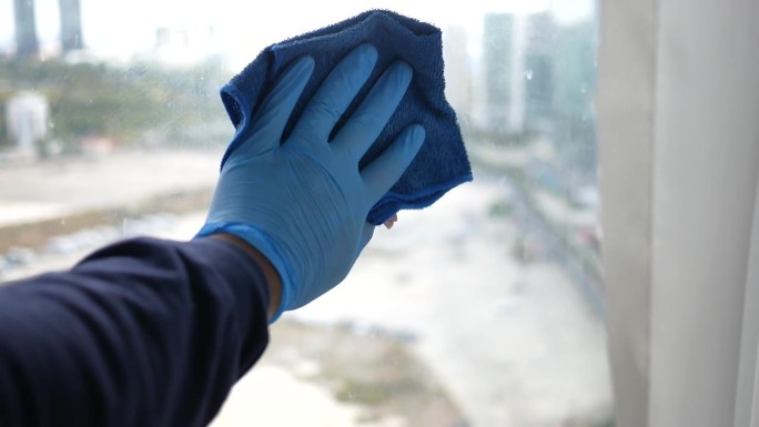 一名男子戴着手套用毛巾擦窗户玻璃的镜头