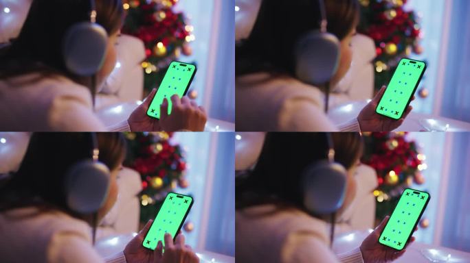 女人手拿绿屏智能手机舒适的家近距离。