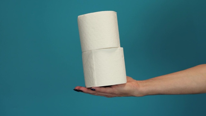 人们正在囤积卫生纸，以便在家隔离冠状病毒。一个女人拿着许多卷卫生纸。